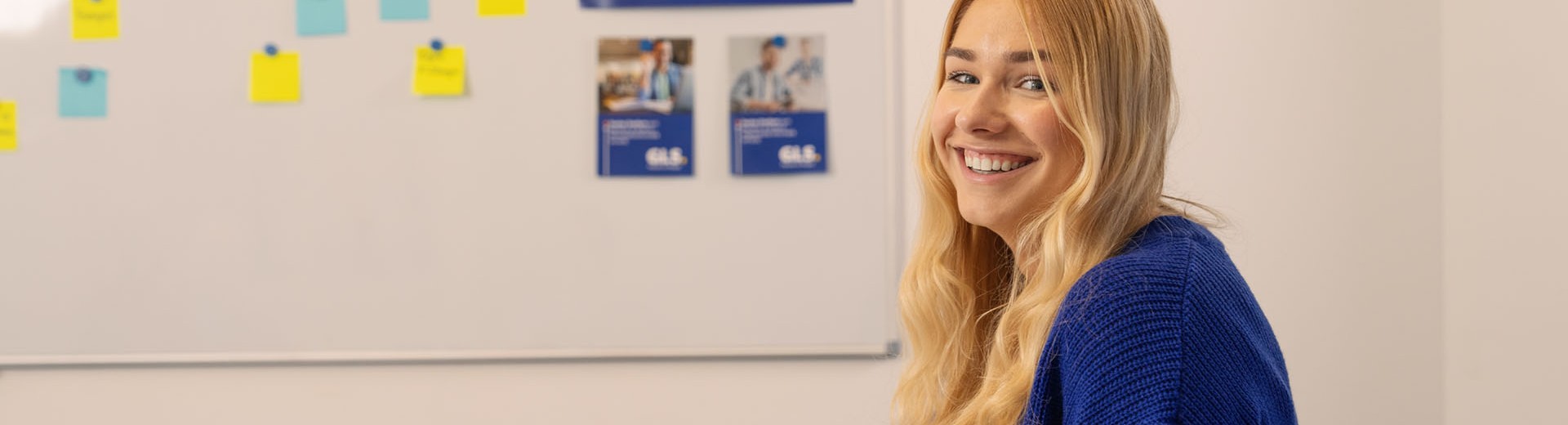 Dual student sits in the meeting room and smiles at the camera