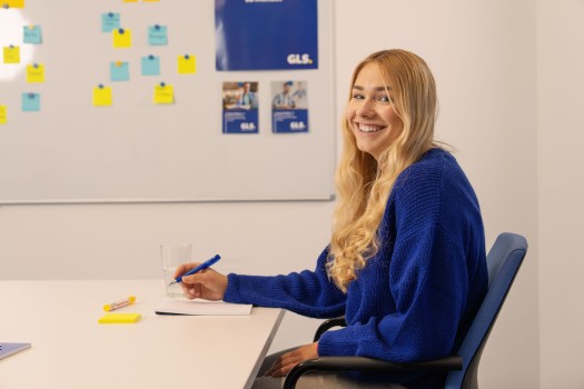 Dual student sits in the meeting room and smiles at the camera