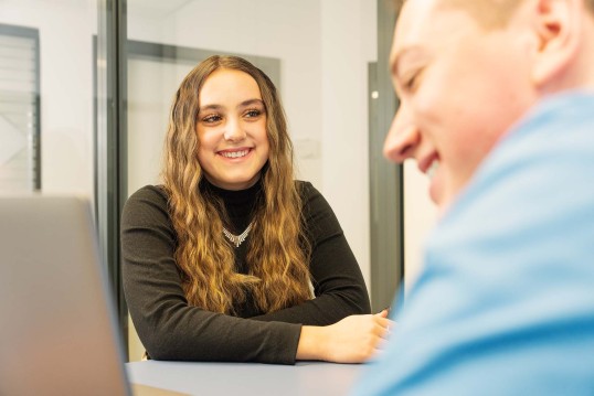Young Talents working together and one smiles at the other 
