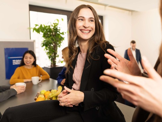 Employee in the office kitchen laughs at her colleague
