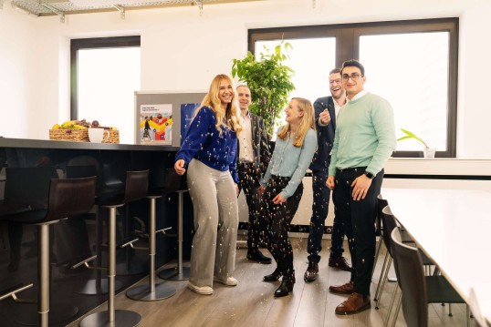 Employees laughing in the office kitchen and throwing confetti