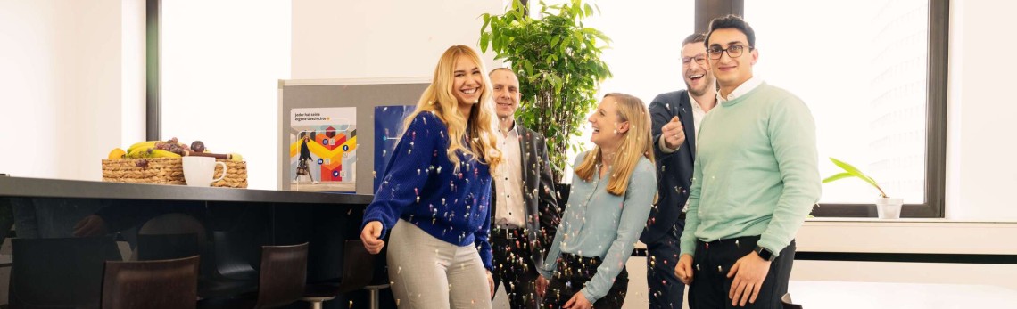 Employees laughing in the office kitchen and throwing confetti