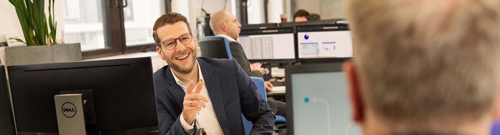 IT employee at his desk laughing at his colleague