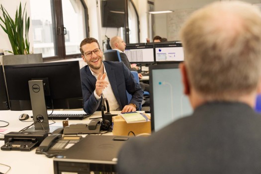 IT employee at his desk laughing at his colleague