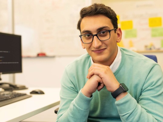 Young professional sits at the desk and looks into the camera