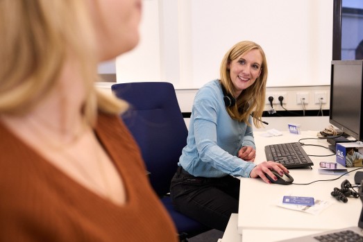 It Employees at the desk smiling to her colleague 