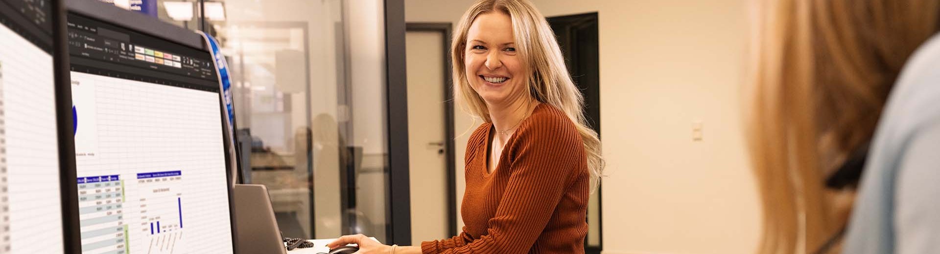 Employee in the open office space is smiling at her colleague