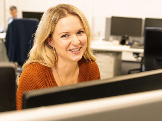 Employee working at the desktop and smiling into the camera