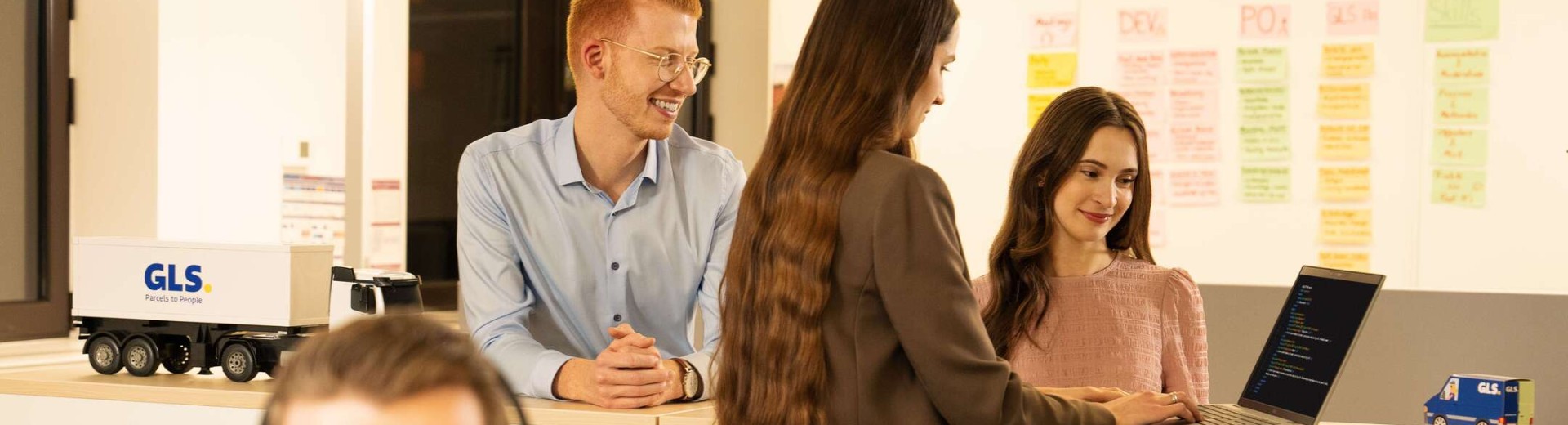 Employees are in conversation and look at a laptop together
