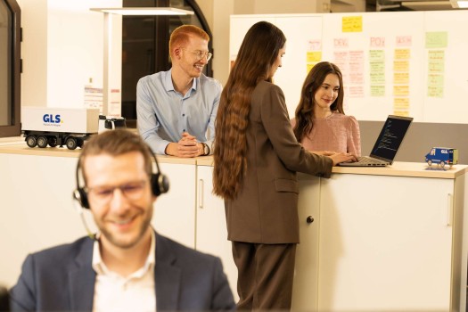 Employees are in conversation and look at a laptop together
