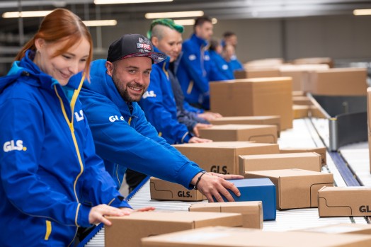 Depot employees on the conveyor belt, one is smiling into the camera