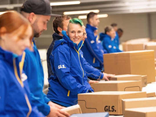 Employees sort parcels and one smiles into the camera
