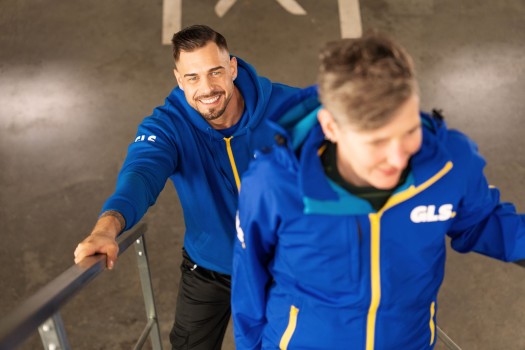 Two employees walk up a flight of stairs together in the hall