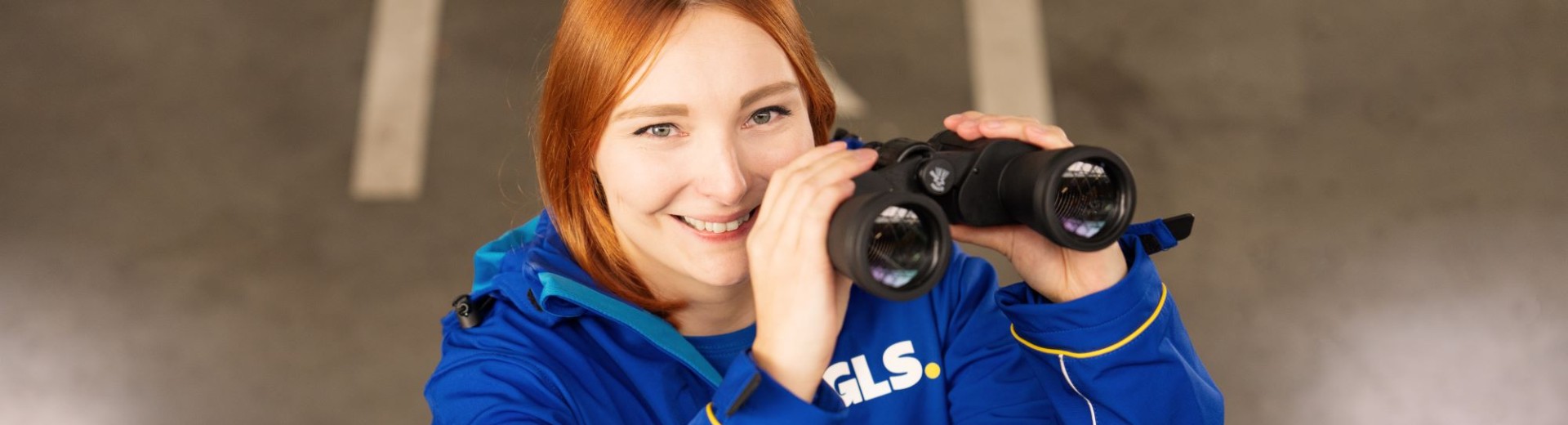 Employee has binoculars in her hand and smiles at the camera