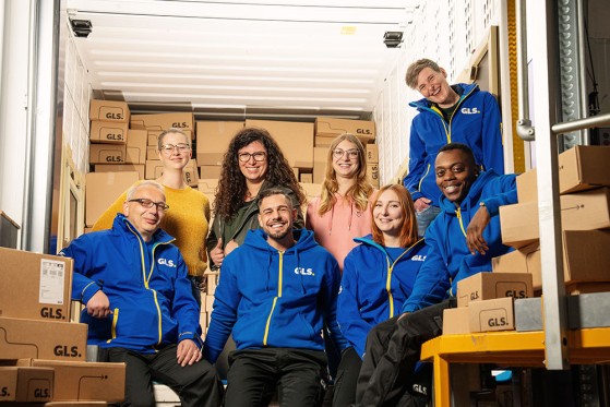 Emploees stand among packages and smiling at the camera 