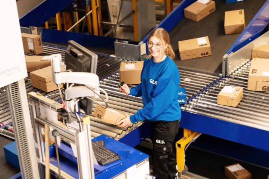 Employee scans parcels in front of the conveyor belt in the depot