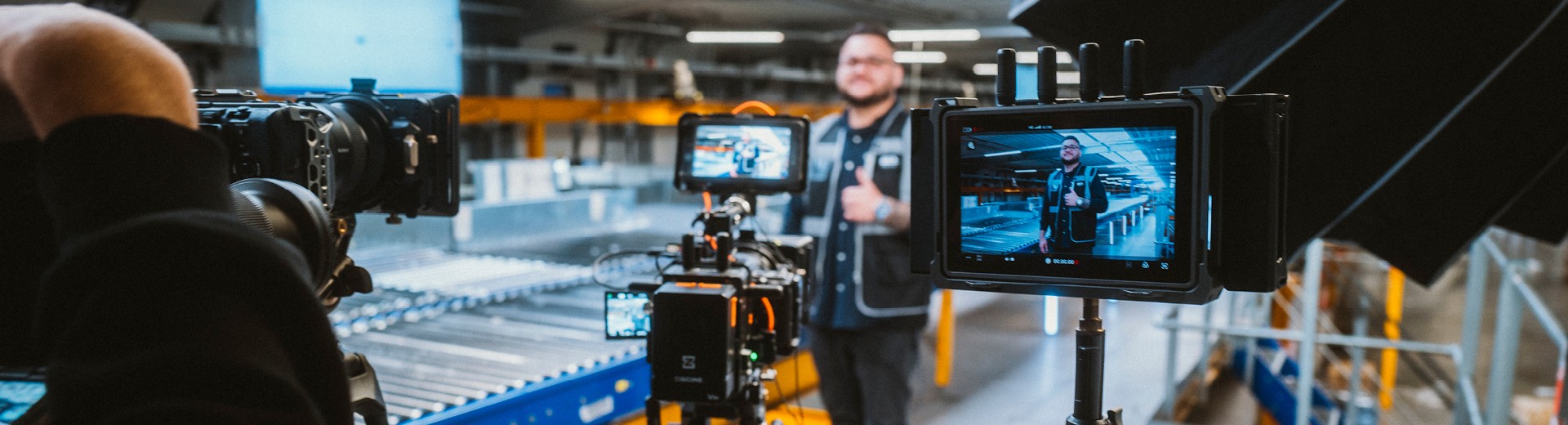 An employee stands in the hall with his thumbs up and smiles into a camera