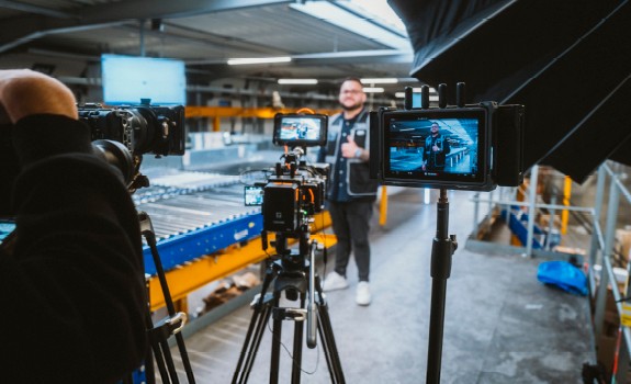 An employee stands in the hall with his thumbs up and smiles into a camera
