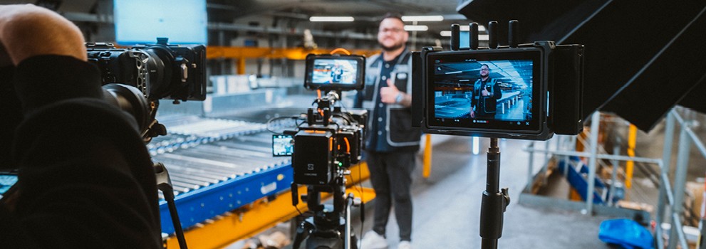 An employee stands in the hall with his thumbs up and smiles into a camera