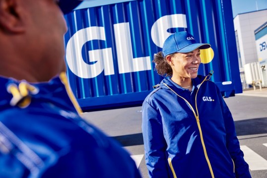 Employees in GLS branded clothing in front of a truck with the GLS logo