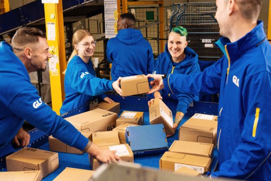 Employees are smiling while sorting packages at the conveyor belt
